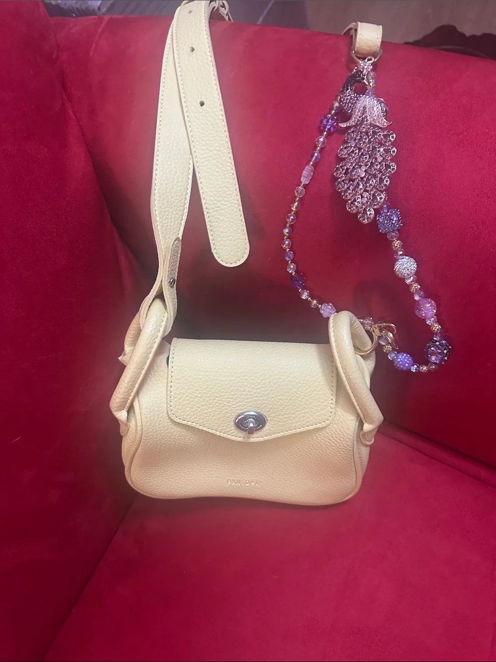 Soft yellow crossbody handbag with charm extension perfect for any occasion
